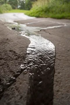 Rainwater Streaming down Asphalt Stock-Fotos