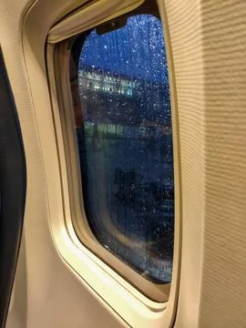 Rainy airplane window with raindrops at dusk Photos