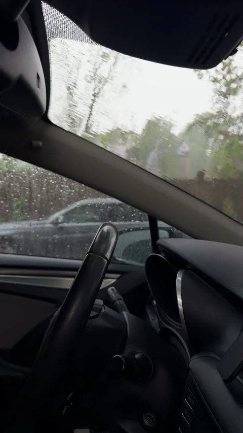 Rainy car interior with blurred windshield view and dark dashboard in parked Stock Footage 345607857