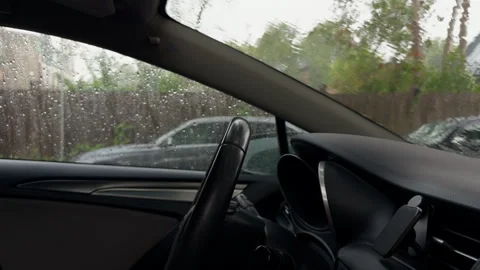 Rainy car interior viewed through side window with dashboard, steering wheel Stock Footage 345610133