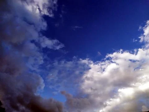 Rainy clouds flying in blue sky Stock Photos