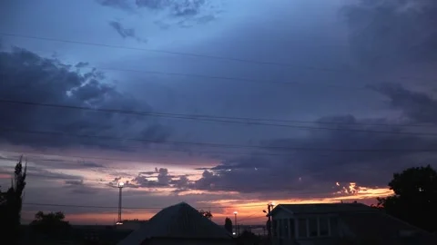 Rainy clouds moving slowly in blue sky on warm summer orange sunset, cinematic c Stock Footage 161370412