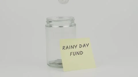 Rainy day fund text or word on yellow notes on empty jar hand inserting coin Stock Footage 307089000
