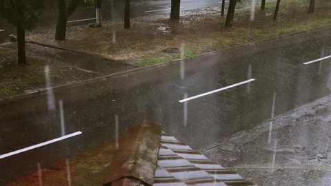 A rainy day scene with raindrops falling on an urban street, creating a tranquil Stock Footage 313501031