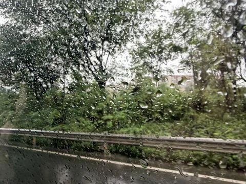 Rainy Day View Through Car Window with Blurred Trees and Road Stock-Fotos