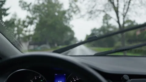 Rainy drive seen through car windshield with moving wipers and blurred tree Stock Footage 344771719