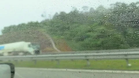 Rainy Drive View Through Car Window with Raindrops, Blurred Highway and Trees Stock Footage 325415255