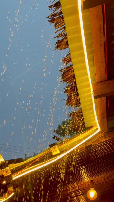 Rainy Evening Dining at a Seaside Resort with Water Streaming from Tin Roof. Видео 340529560