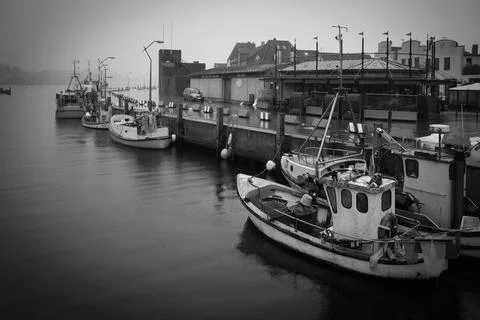 Rainy harbor scene in Eckernfrde, Germany, featuring small fishing boats mo.. Stock Photos