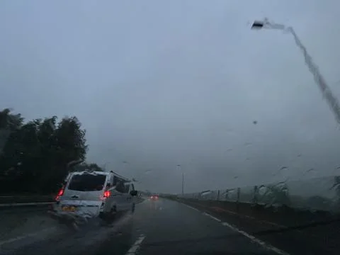 Rainy highway commute seen through windshield with blurred van ahead, wet Stock Photos
