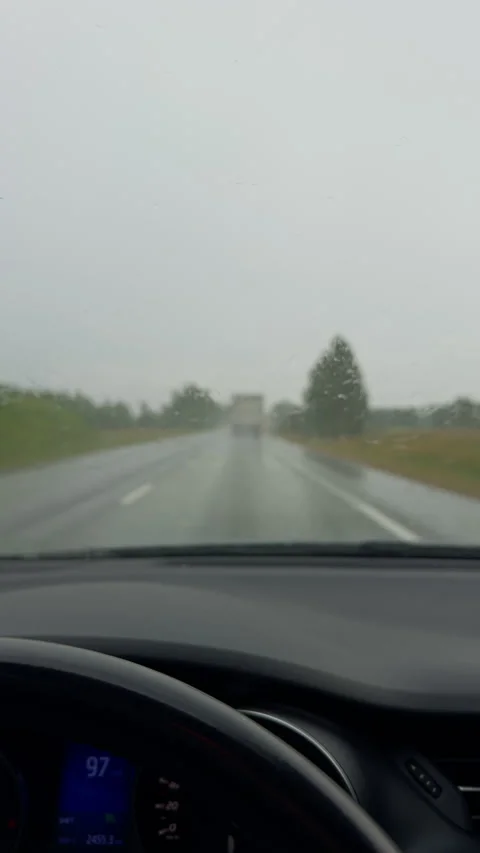 Rainy highway drive seen through windshield with wipers clearing wet road and Stock Footage 345452431