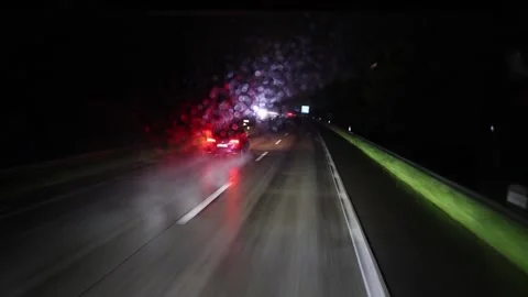 Rainy highway at night with blurred car taillights and reflections glowing on we Stock Footage 310856571