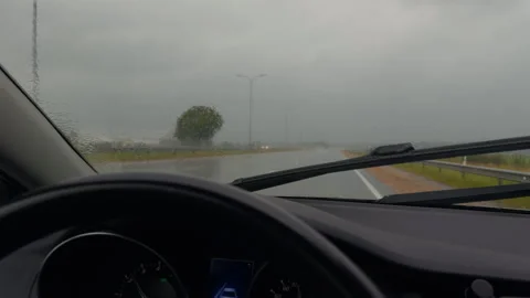 Rainy highway seen through car windshield with moving wipers and gray overcast Stock Footage 345530348