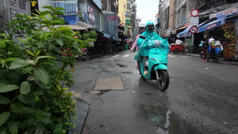 Rainy morning on Bui Vien Walking Street as mopeds drive through Ho Chi Minh Stock Footage 305448853