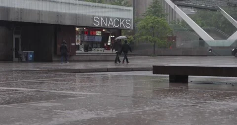 Rainy Nathan Phillips Square with snacks kiosk and people under umbrellas Stock Footage 321035548