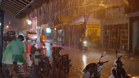 Rainy night, a man in a raincoat prepares a scooter for a trip Stock-Footage 252515506