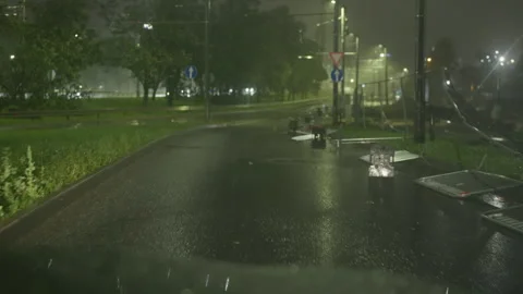 Rainy night road with wet pavement, glowing streetlights, mist, and empty urban Stock Footage 345533849