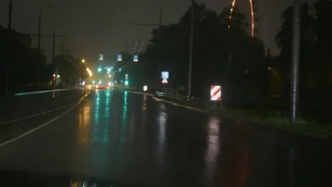 Rainy night road with wet reflections, blurred traffic lights and empty urban Stock Footage 345533434