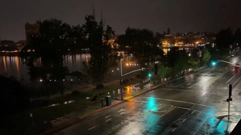 Rainy night traffic on a street beside a city lake Stock Footage 240370853