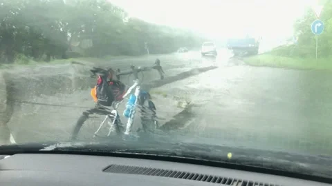 Rainy road with bicycle standing on roadside through wind-screen in car 스톡 동영상 155444082