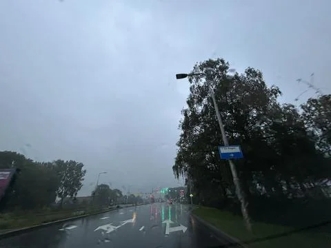 Rainy road intersection viewed through wet windshield with blurred traffic Stock Photos