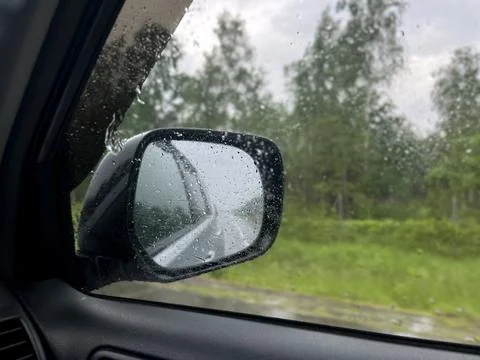 Rainy road trip view through car side mirror with water drops Stock Photos