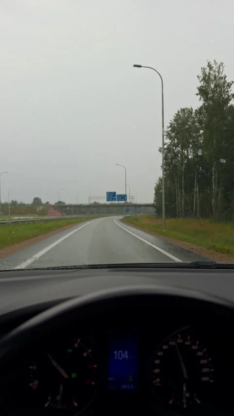 Rainy road view from car interior with windshield wipers and empty curving Stock Footage 345452344
