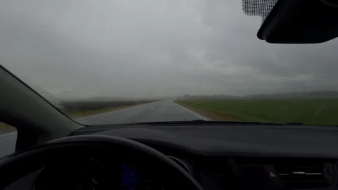 Rainy road viewed through car windshield with wipers moving across misty Stock Footage 345763284