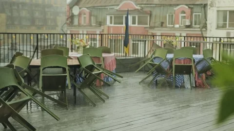 Rainy scene with rooftop dining area with overturned chairs and tables. The Stock-Footage 318066127