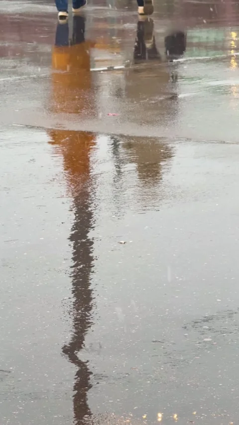 Rainy street with pedestrians walking while their reflection appears in large Video stock 330122610