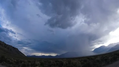 Rainy time-lapse with storm clouds starting to break over distant mountains 库存影片 166417016