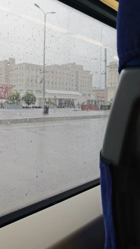 Rainy train ride shows view outside window with drops on glass in city setting Stock Footage 345516985