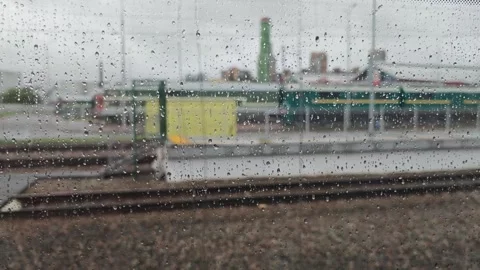 Rainy train ride shows view outside window with drops on glass in city setting Stock Footage 345517185