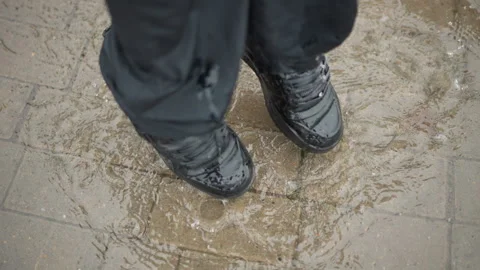 Rainy urban reflection. Closeup of boots on wet city tiles. An intimate Stock Footage 346455462