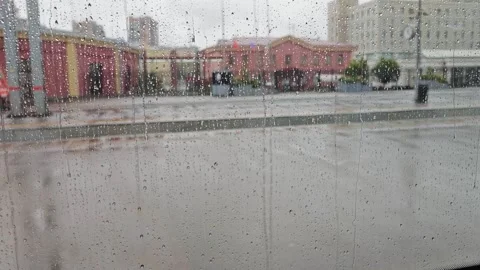 Rainy view from a commuter train window: wet glass with droplets and streaks Stock Footage 346454099