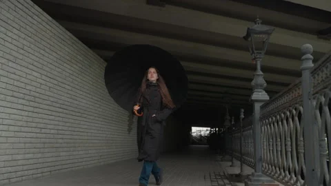 Rainy walk beneath underground arch. Solo traveler moves through shadowy Vidéo 328035297
