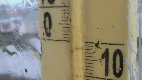 Rainy weather outside. Drops on the window glass, foggy thermometer scale Stock Footage 125662442