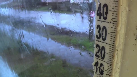 Rainy weather outside. Drops on the window glass, foggy thermometer scale Stock Footage 125912521