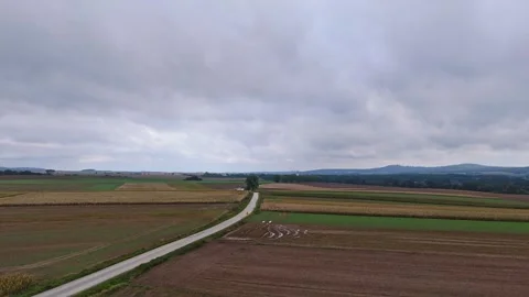 A rainy, winding road between fields captured by drone. The horizon shows a.. Video stock 285022811