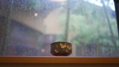 Rainy window behind Japanese tea cup on a wooden window sill Stock Footage 157666484