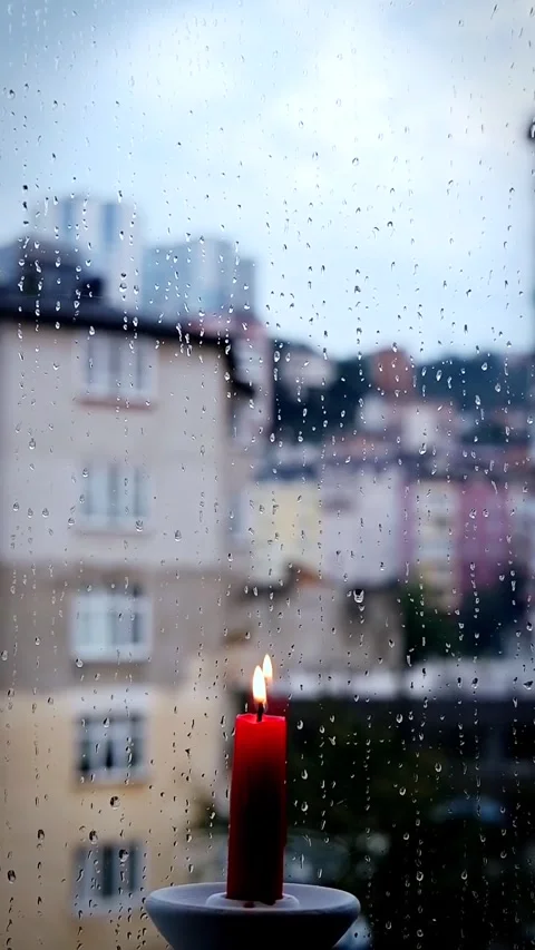 Rainy Window with Lit Red Candle and City View Stock Footage 326723290