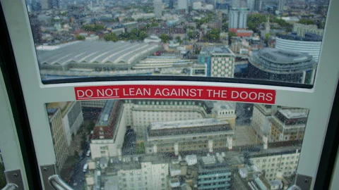 Rainy window view with a warning sign and city buildings below. Stock Footage 319807920