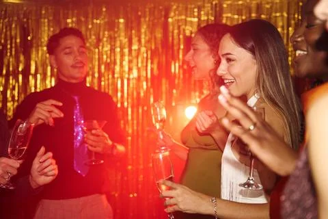 Raised drinks and dancing beneath metallic gold fringe Fotos de archivo
