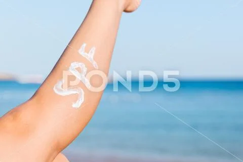 Raised up female leg with spf word made of sun cream at the beach. Sun protec Stock Photos