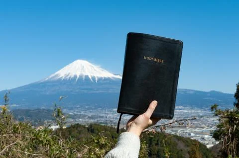 Raised hand holding the Holy Bible. Background Mount Fuji. Stock Photos