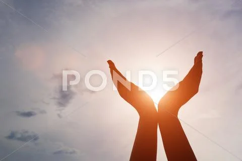 Raised hands catching sun on sunset sky. Concept of spirituality, wellbeing, Stock Photos