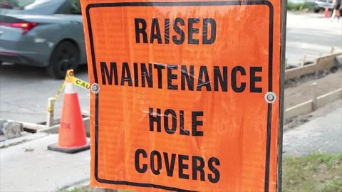 Raised maintenance hole covers square orange black writing text construction Stock Footage 251357314