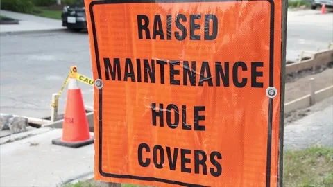 Raised maintenance hole covers square orange black writing text construction Stock Footage 251357371