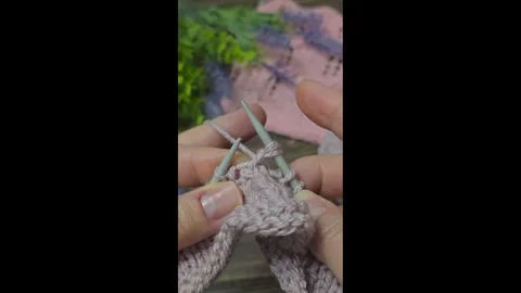 A raised openwork pattern knitted with colored yarn on a wooden background. Stock Footage 332404045