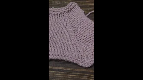 A raised openwork pattern knitted with colored yarn on a wooden background. Stock Footage 332404355